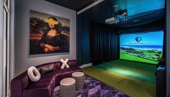 A home theater with a purple couch and a painting on the wall